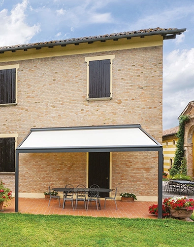 Tenda bianca che fa da schermatura solare al tavolo in giardino
